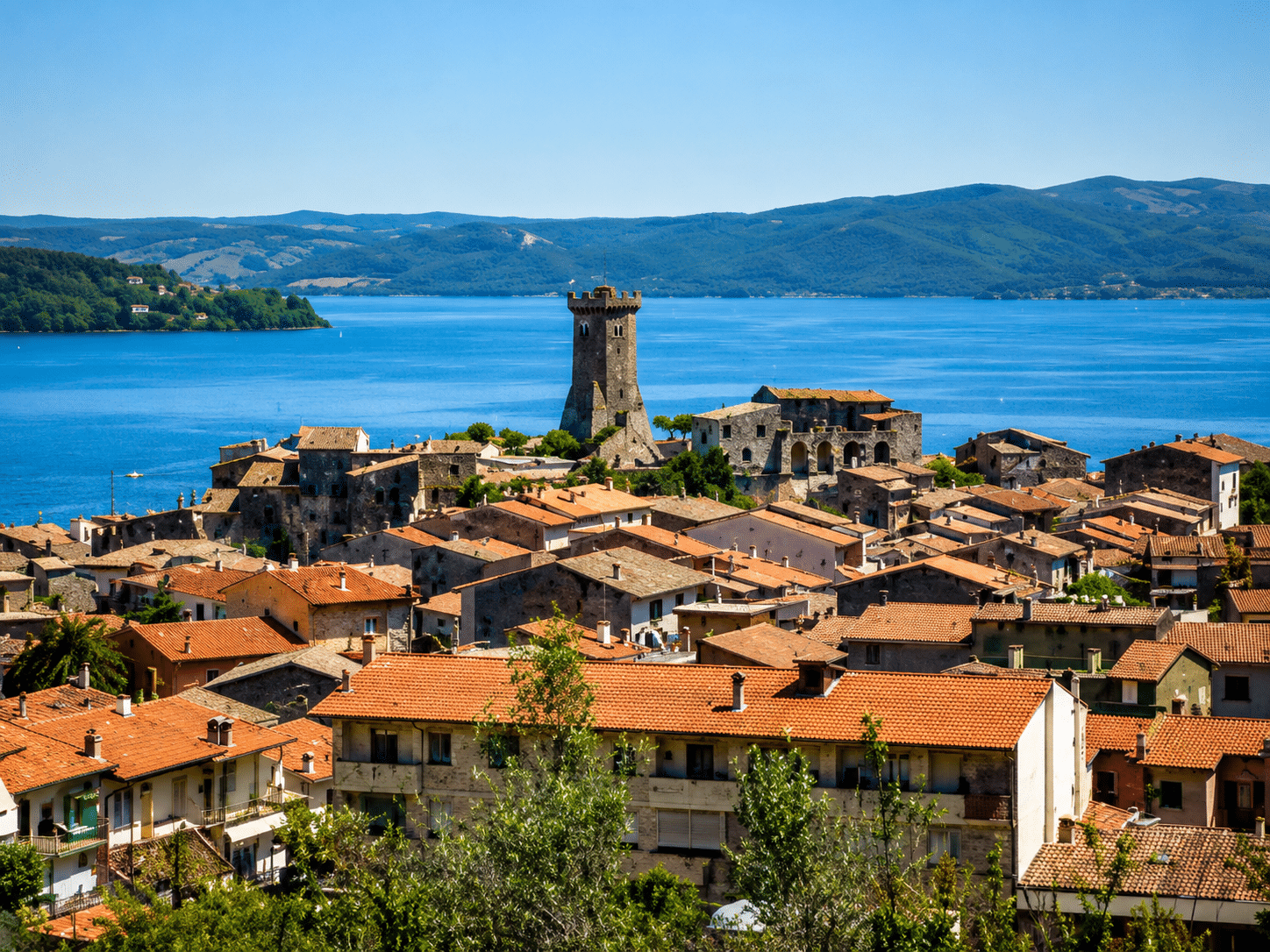Vista di un borgo con lago e montagne.
