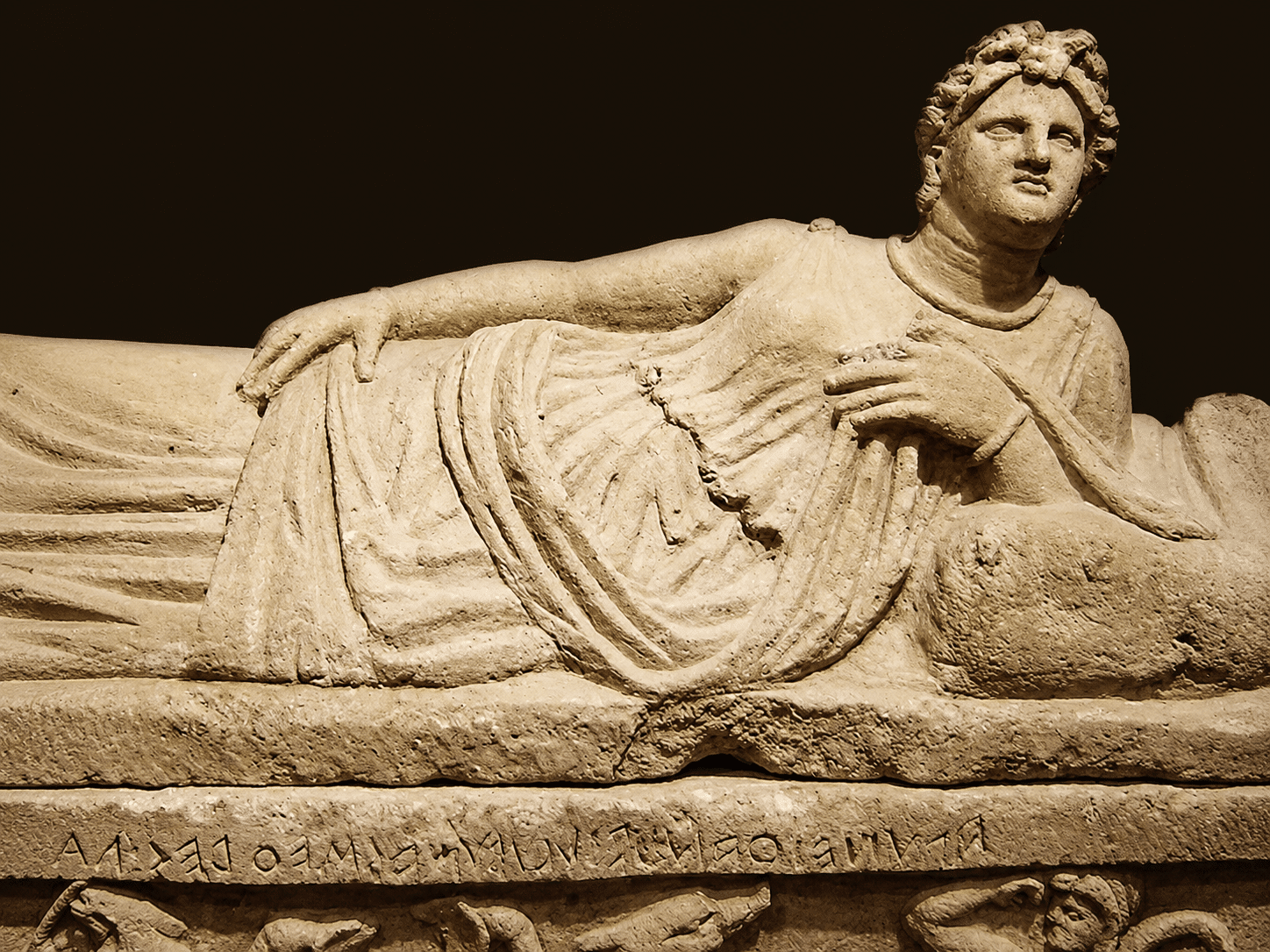 Statua di figura reclinata su sarcofago antico.