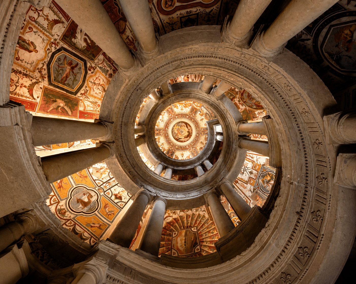 Scala a chiocciola con affreschi colorati sul soffitto.