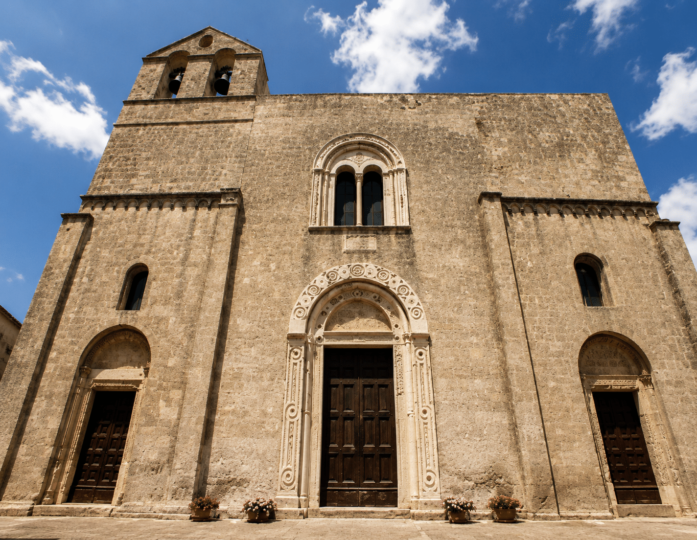 Facciata di una chiesa in pietra con cielo azzurro.
