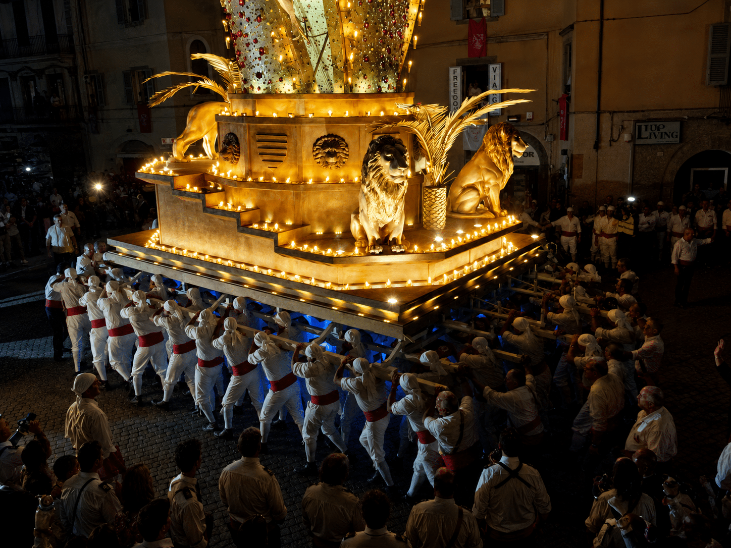 Persone trasportano una struttura illuminata durante una processione.