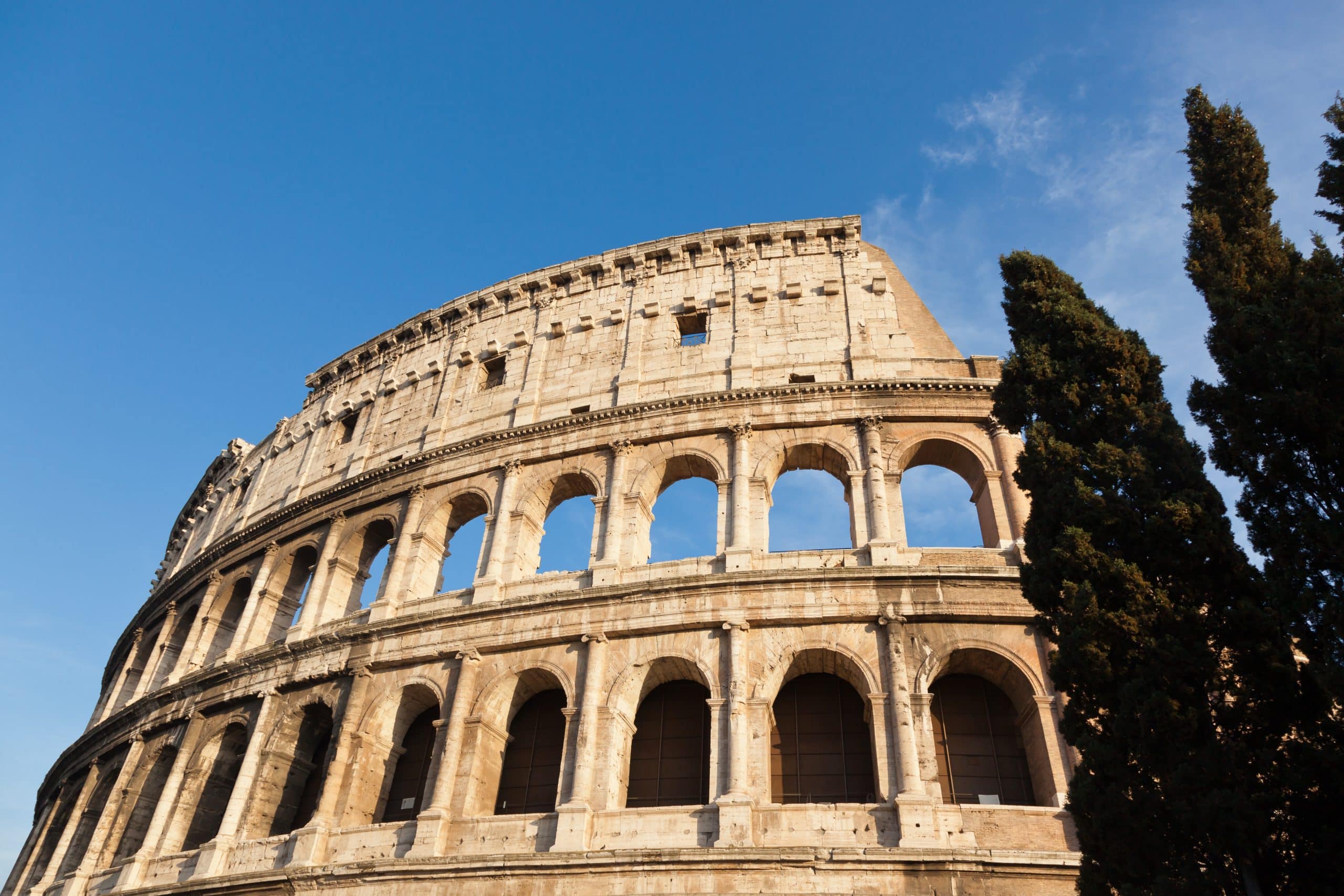 Colosseo con cielo azzurro e alberi.